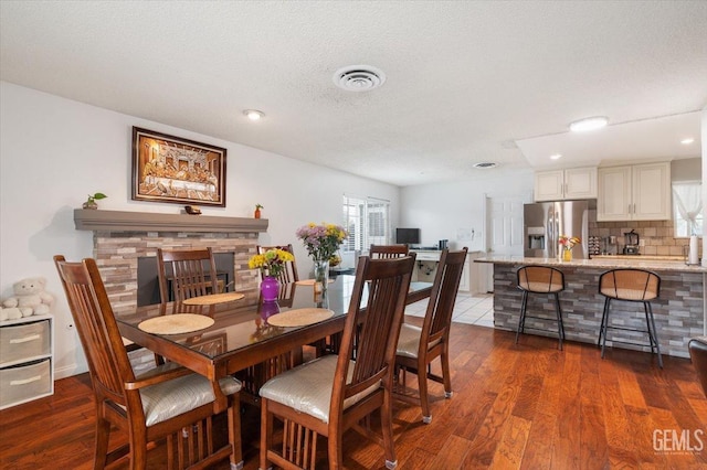 dining space with recessed lighting, a textured ceiling, visible vents, and dark wood-style flooring