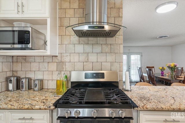 kitchen featuring visible vents, backsplash, range hood, light stone countertops, and appliances with stainless steel finishes