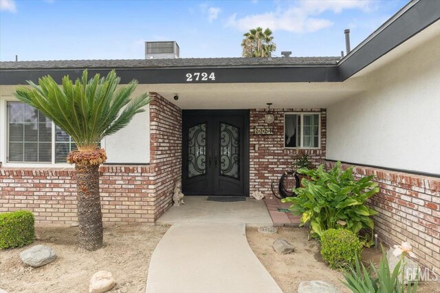 property entrance featuring stucco siding, brick siding, a porch, and a chimney