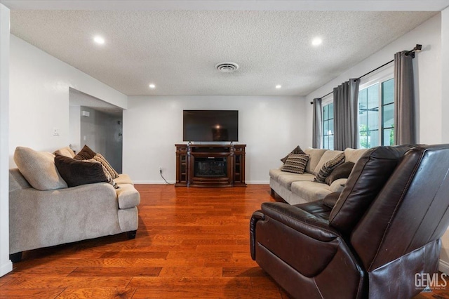 living room with recessed lighting, a textured ceiling, wood finished floors, and visible vents