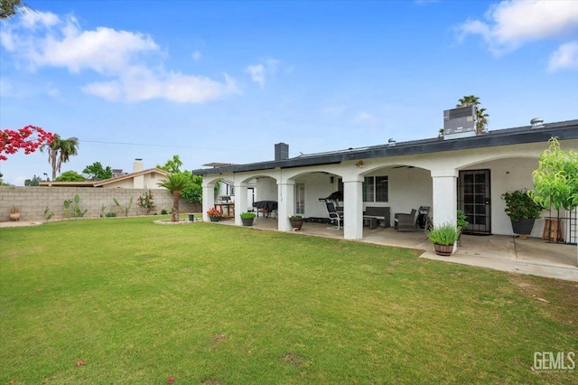 rear view of house featuring a chimney, fence, stucco siding, a patio area, and a lawn