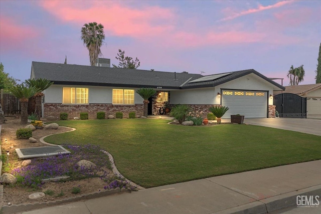 ranch-style home with driveway, brick siding, a garage, roof mounted solar panels, and stucco siding