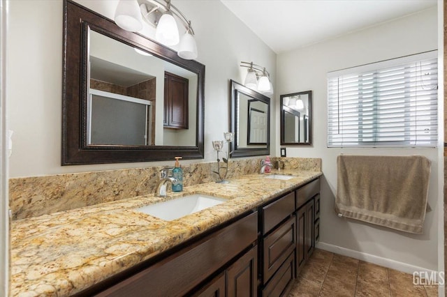 bathroom featuring a shower stall, baseboards, a sink, and double vanity