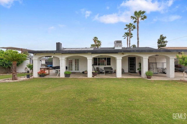 back of property featuring a lawn, french doors, a patio area, and stucco siding