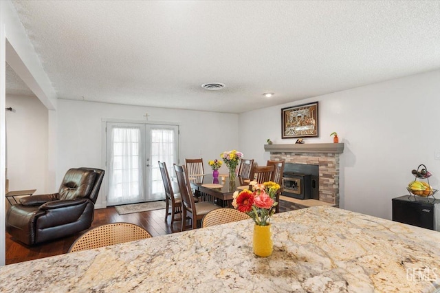 dining room with a textured ceiling, wood finished floors, visible vents, and french doors