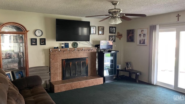 living room with a textured ceiling, ceiling fan, carpet floors, and a tile fireplace