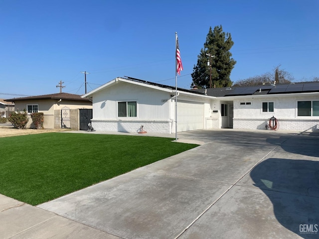 ranch-style home with a garage, a front yard, and solar panels