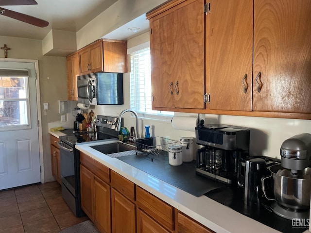 kitchen with ceiling fan, electric stove, dark tile patterned flooring, and sink