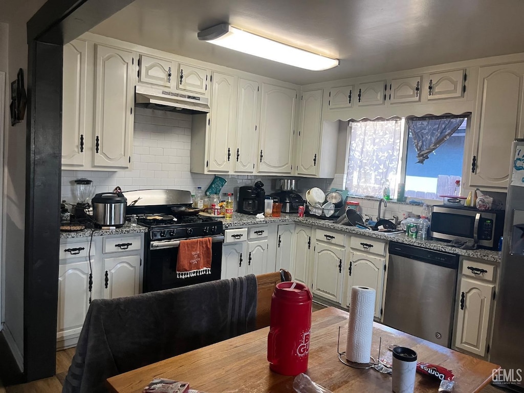 1112 Meredith Dr, Bakersfield, CA 93304 - kitchen with a sink, stainless steel appliances, under cabinet range hood, white cabinetry, and decorative backsplash
