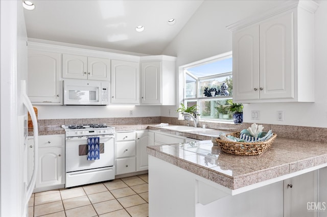 48 16th St, Cayucos, CA 93430 - kitchen featuring white appliances, tile counters, vaulted ceiling, a peninsula, and white cabinetry