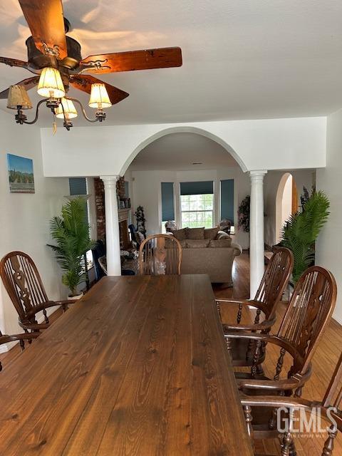 dining space featuring hardwood / wood-style flooring, ceiling fan, and decorative columns