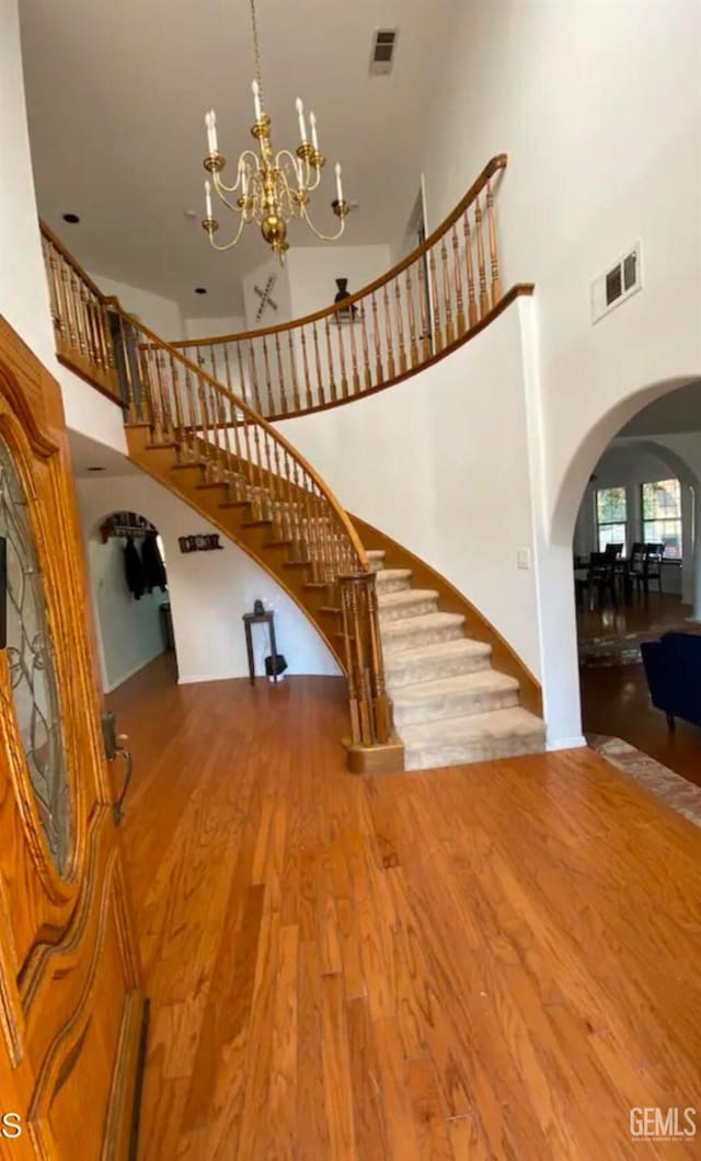 stairway featuring hardwood / wood-style flooring, a notable chandelier, and a towering ceiling