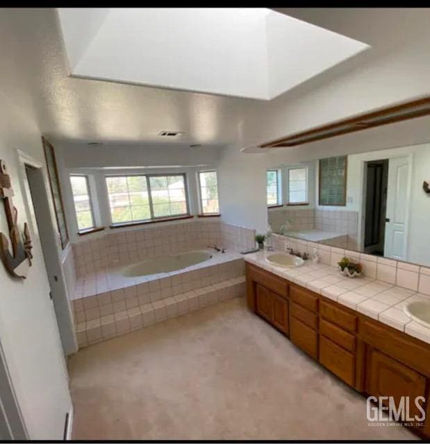 bathroom featuring vanity and a relaxing tiled tub