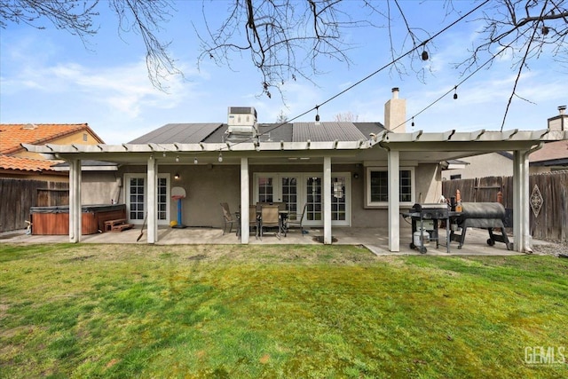 rear view of property featuring a yard, a hot tub, a fenced backyard, and a patio