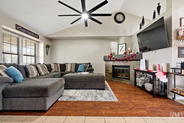 tiled living room with high vaulted ceiling, ceiling fan, and a stone fireplace