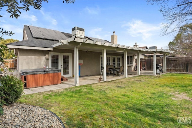 back of house with a patio, a fenced backyard, solar panels, french doors, and a hot tub