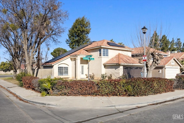 mediterranean / spanish home featuring a garage and solar panels