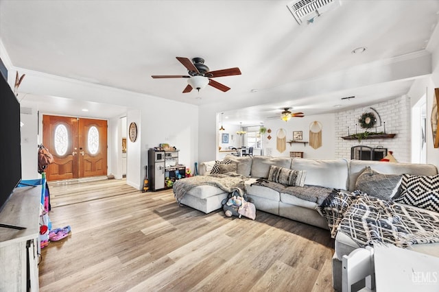 living room featuring ceiling fan, a fireplace, and light hardwood / wood-style flooring