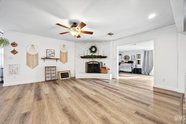 unfurnished living room featuring wood-type flooring, a brick fireplace, crown molding, and ceiling fan