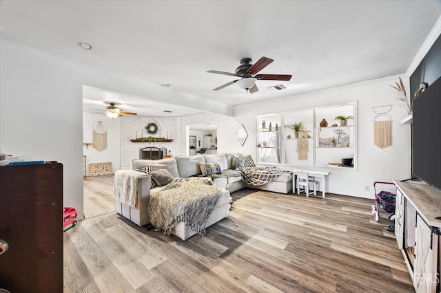 living room with crown molding, ceiling fan, a fireplace, and hardwood / wood-style floors