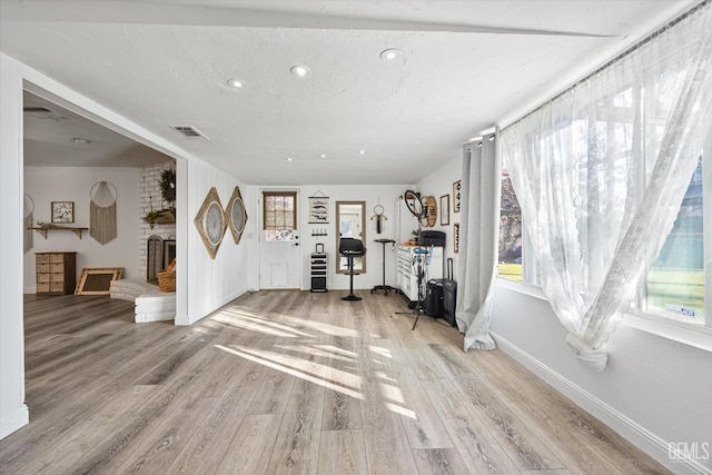 entrance foyer featuring a textured ceiling, a fireplace, and light wood-type flooring