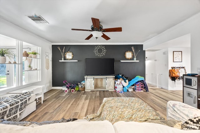 living room featuring hardwood / wood-style floors, crown molding, and ceiling fan