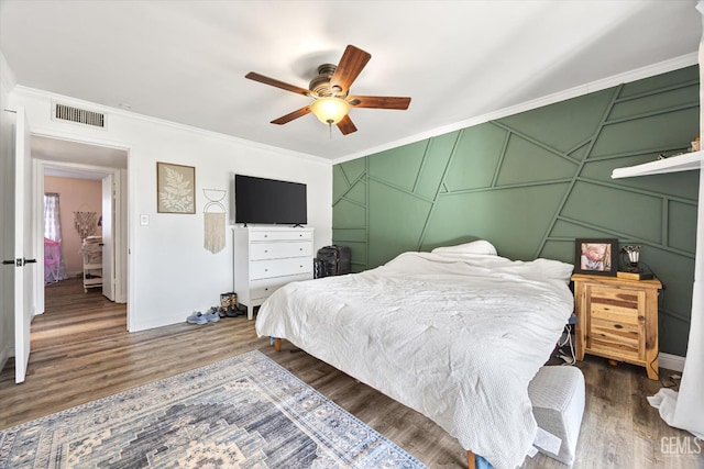 bedroom with crown molding, ceiling fan, and dark wood-type flooring