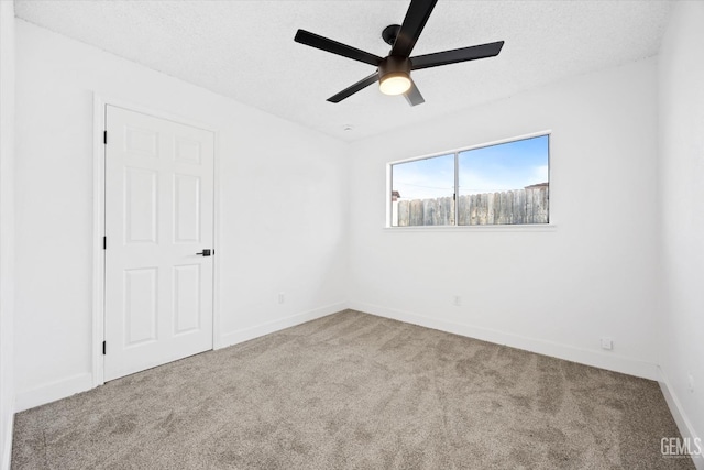 carpeted empty room with ceiling fan and a textured ceiling