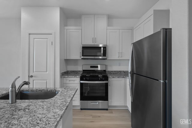 kitchen featuring light stone counters, appliances with stainless steel finishes, sink, and white cabinets