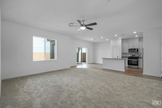 unfurnished living room featuring light colored carpet and ceiling fan