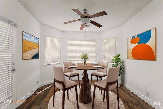 dining area featuring a ceiling fan, baseboards, and dark wood-type flooring