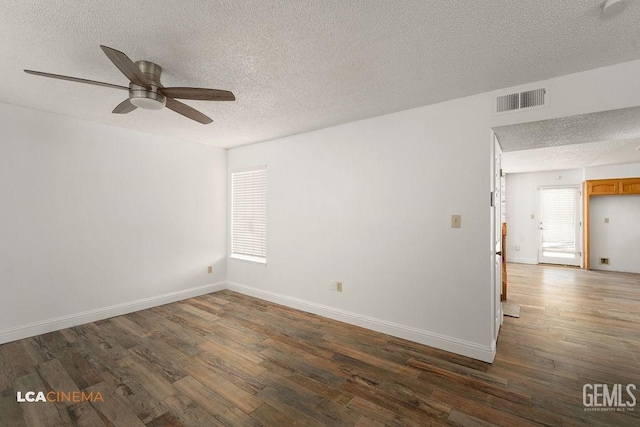 unfurnished room with dark wood-style flooring, visible vents, a textured ceiling, and baseboards