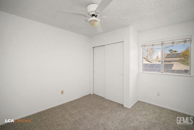 unfurnished bedroom with carpet, a closet, a textured ceiling, and baseboards