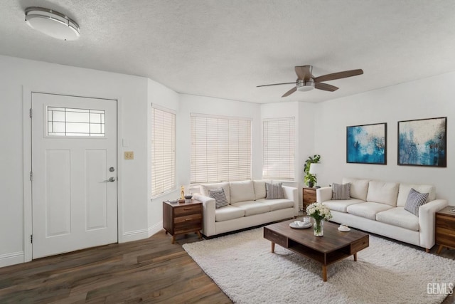 living area with dark wood-style floors, a textured ceiling, a ceiling fan, and baseboards