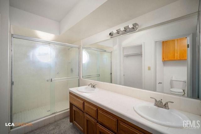 full bathroom with double vanity, a stall shower, and a sink