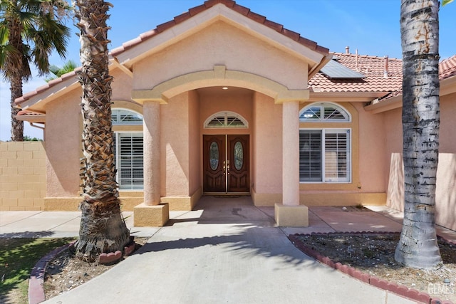 200 Justin Ct, Shafter, CA 93263 - property entrance featuring stucco siding, roof mounted solar panels, and a tiled roof