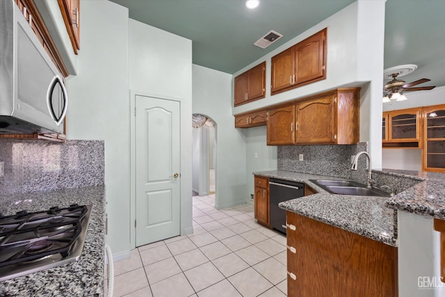 200 Justin Ct, Shafter, CA 93263 - kitchen featuring stainless steel appliances, ceiling fan, brown cabinetry, tasteful backsplash, and dark stone countertops