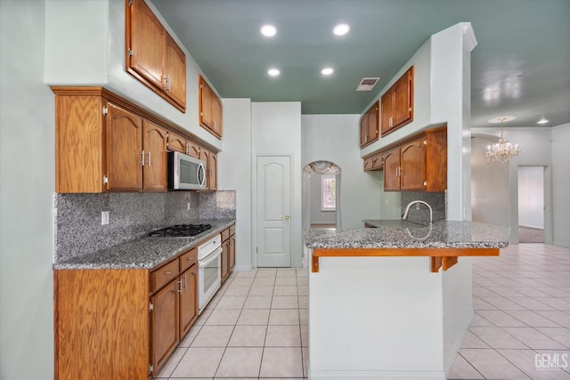 200 Justin Ct, Shafter, CA 93263 - kitchen featuring a peninsula, appliances with stainless steel finishes, light tile patterned flooring, decorative backsplash, and stone counters