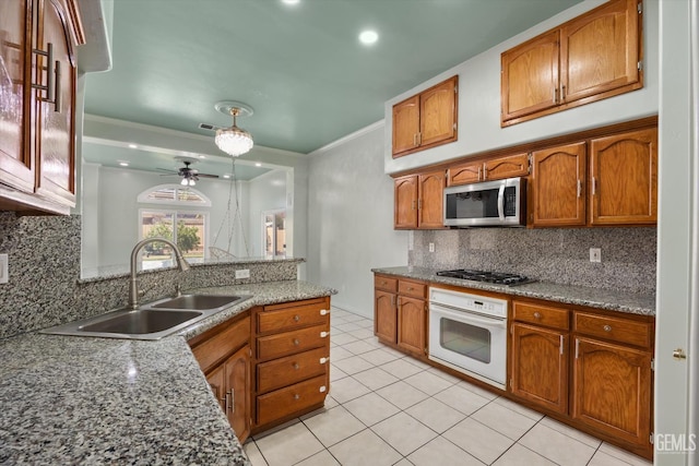 200 Justin Ct, Shafter, CA 93263 - kitchen with appliances with stainless steel finishes, brown cabinets, ceiling fan, light tile patterned floors, and decorative backsplash