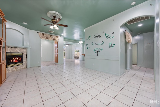 200 Justin Ct, Shafter, CA 93263 - unfurnished living room with ceiling fan, a tiled fireplace, ornamental molding, arched walkways, and light tile patterned floors