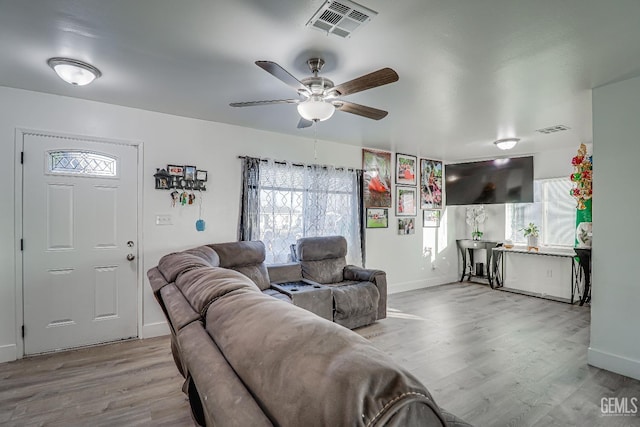 living room featuring plenty of natural light, ceiling fan, and light wood-type flooring