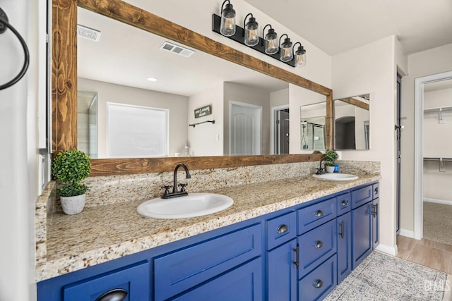 15020 Cotton Blossom Ave, Bakersfield, CA 93314 - bathroom featuring double vanity, a spacious closet, baseboards, and a shower with shower door
