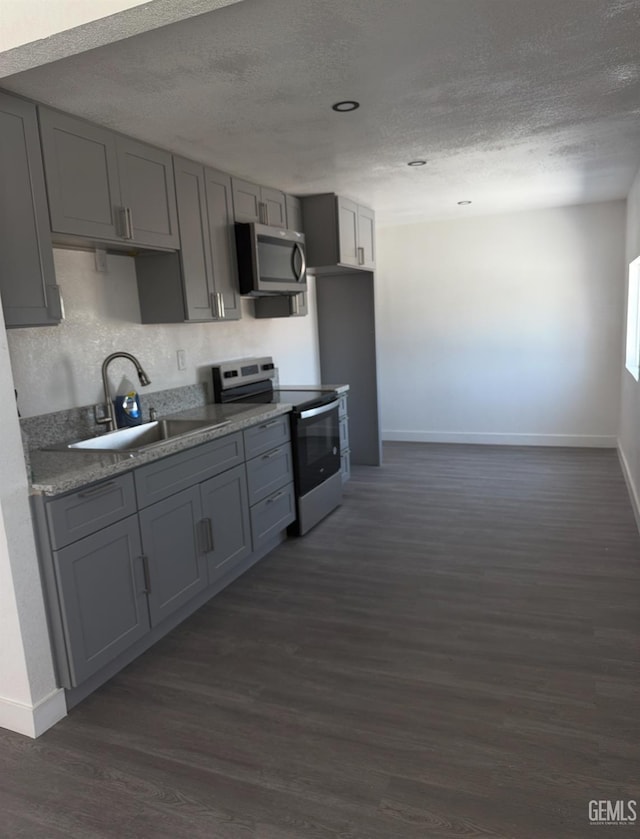 28112 Pond Rd, Wasco, CA 93280 - kitchen with appliances with stainless steel finishes, gray cabinetry, a textured ceiling, and dark wood-style flooring