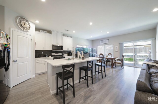 8317 Littleton St, Bakersfield, CA 93314 - kitchen with a kitchen breakfast bar, tasteful backsplash, open floor plan, light wood finished floors, and appliances with stainless steel finishes