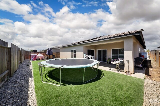 8317 Littleton St, Bakersfield, CA 93314 - rear view of property with stucco siding, a lawn, a fenced backyard, and a trampoline