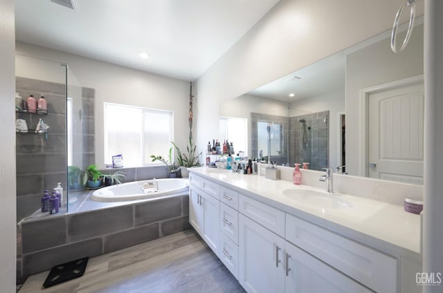 bathroom featuring a shower stall, double vanity, wood finished floors, a sink, and a garden tub