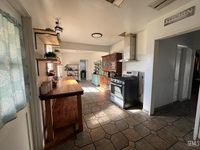 kitchen with gas stove, tile counters, and wall chimney exhaust hood