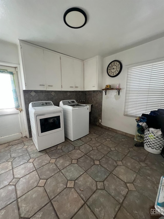 clothes washing area with washer and dryer and cabinets