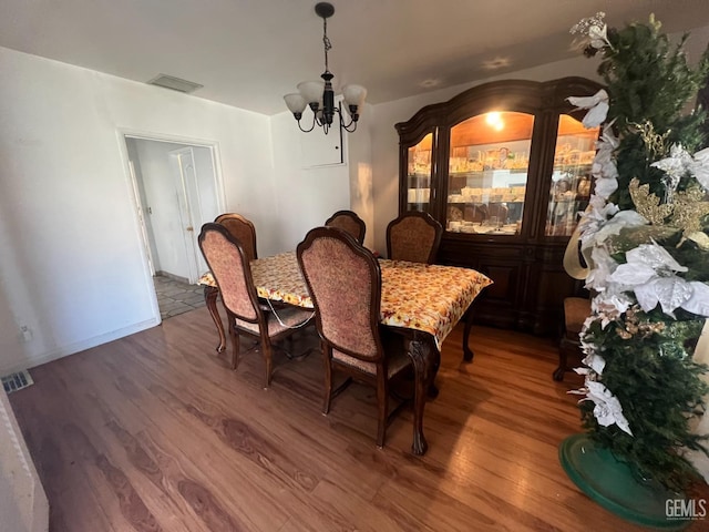 dining room with wood-type flooring and a notable chandelier