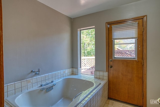 bathroom with tiled tub and tile patterned flooring